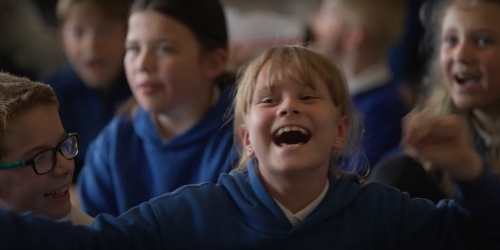 A group of children smiling and singing as part of the Whistling Away project.