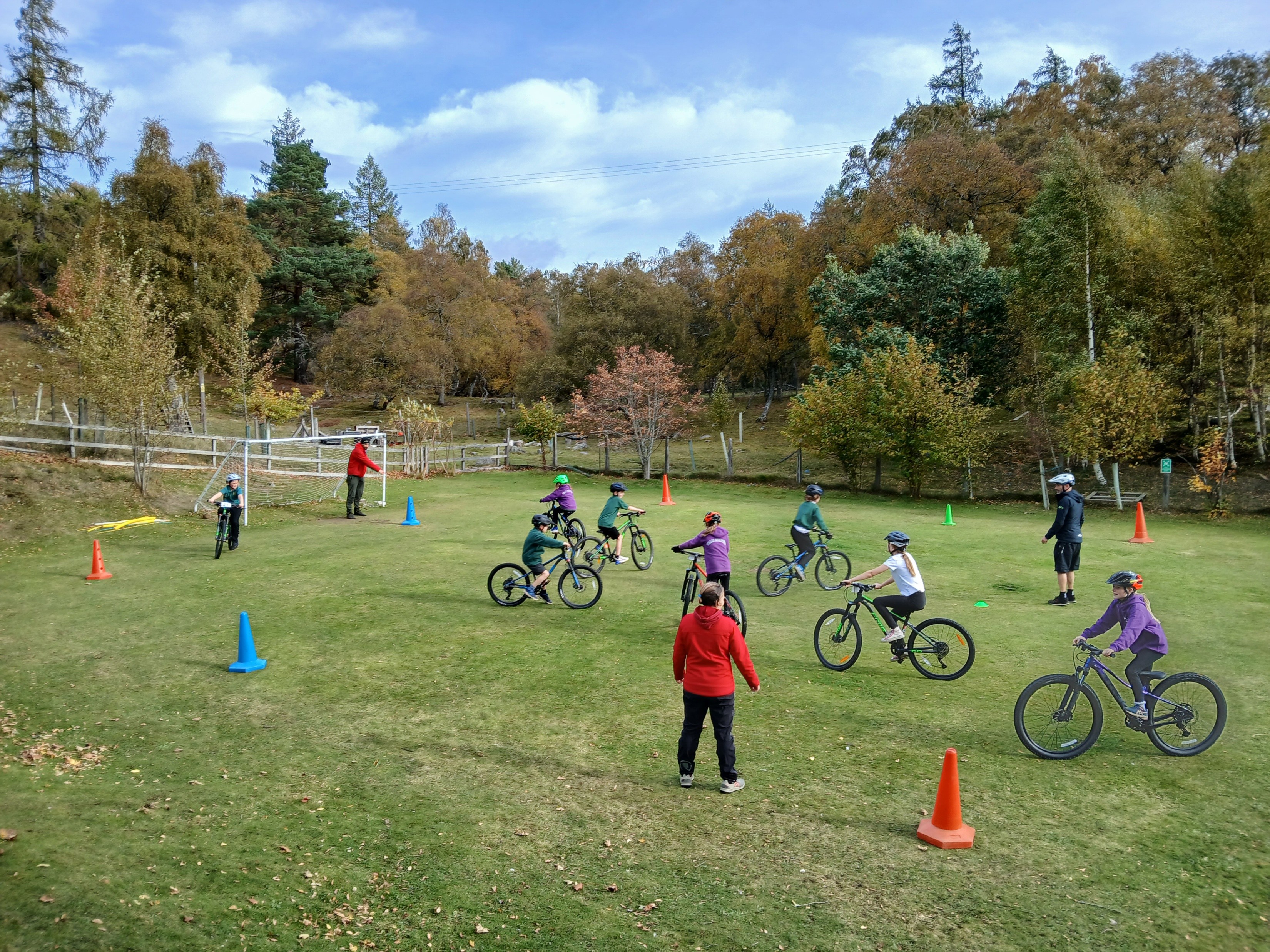 Eight children cycling on a grass field with three cycling instructors