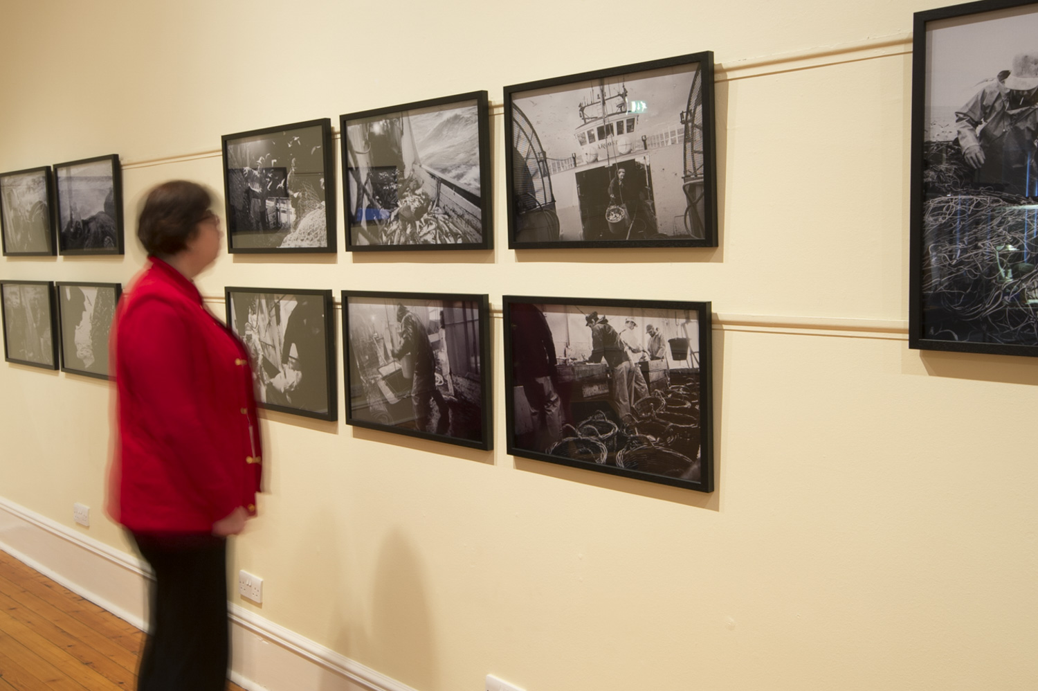 lady looking at a series of framed prints on a wall.