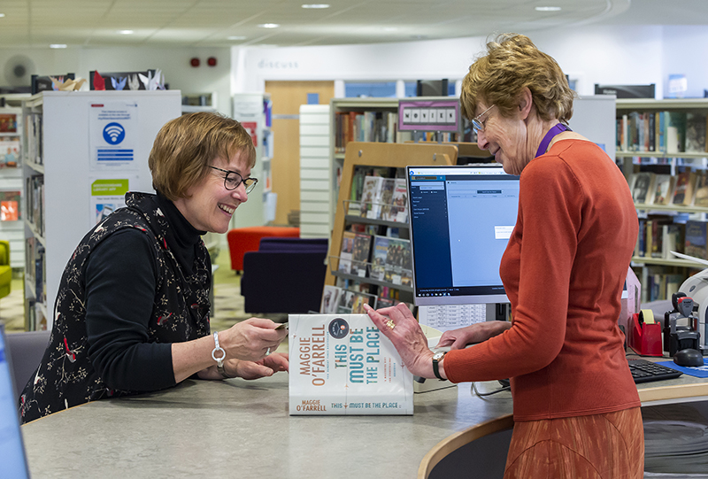 librarian issuing book to customer