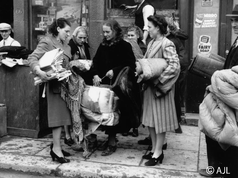 Survivors of an August 1941 raid on Peterhead clutch salvaged possessions. Mrs Cooke (centre in black coat) just managed to reach the shelter as the bomb burst. August 10th 1941.