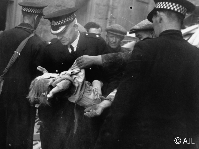 Policemen carrying a child that have saved from a bomb raid