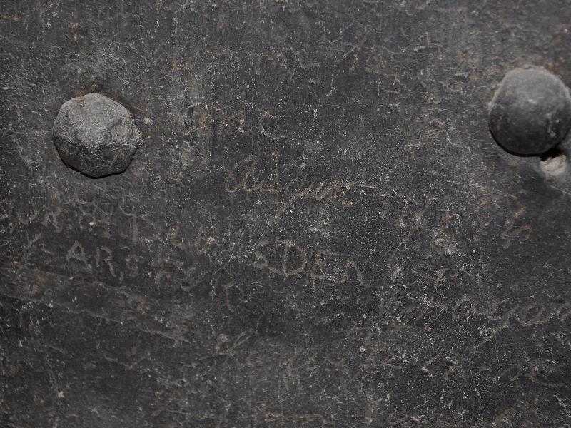 names and dates scratched into a prison door