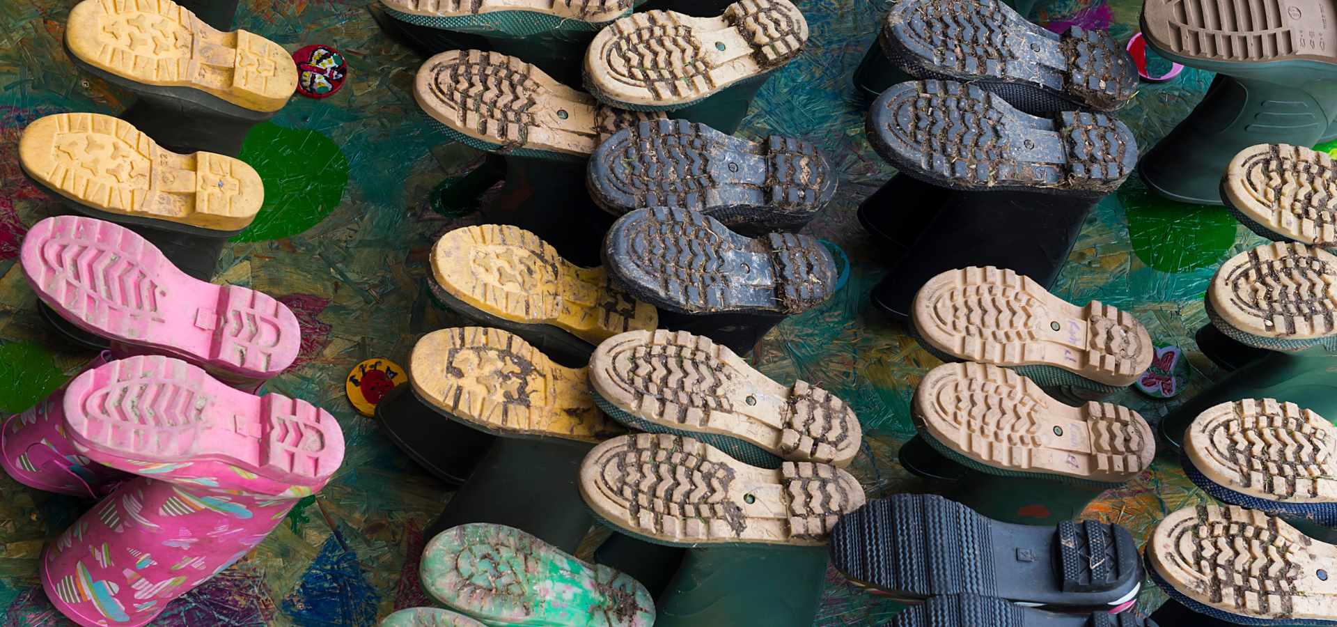 lots of colourful children's welly boots upside down on a boot stand