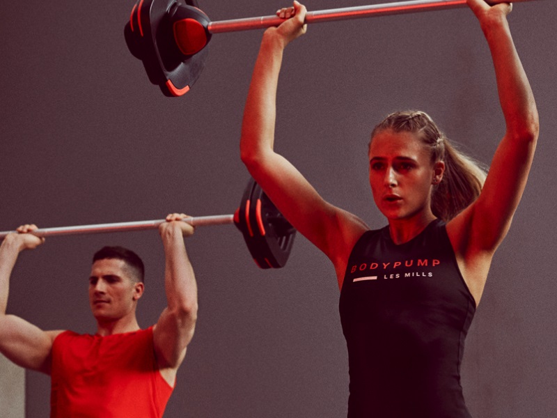 Two people lifting weights and taking part in a body pump class