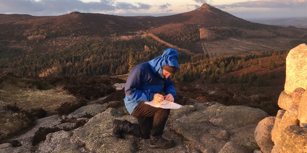 A person at the top of a hill reading a map