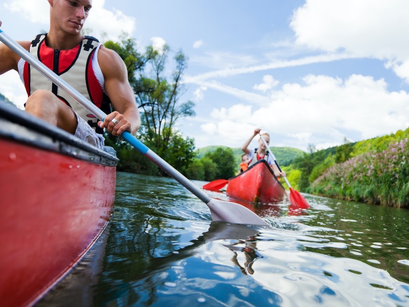 A couple of people canoeing down a river