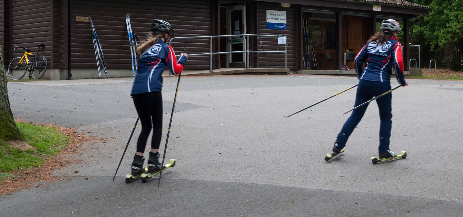 two adults  racing on roller skis 