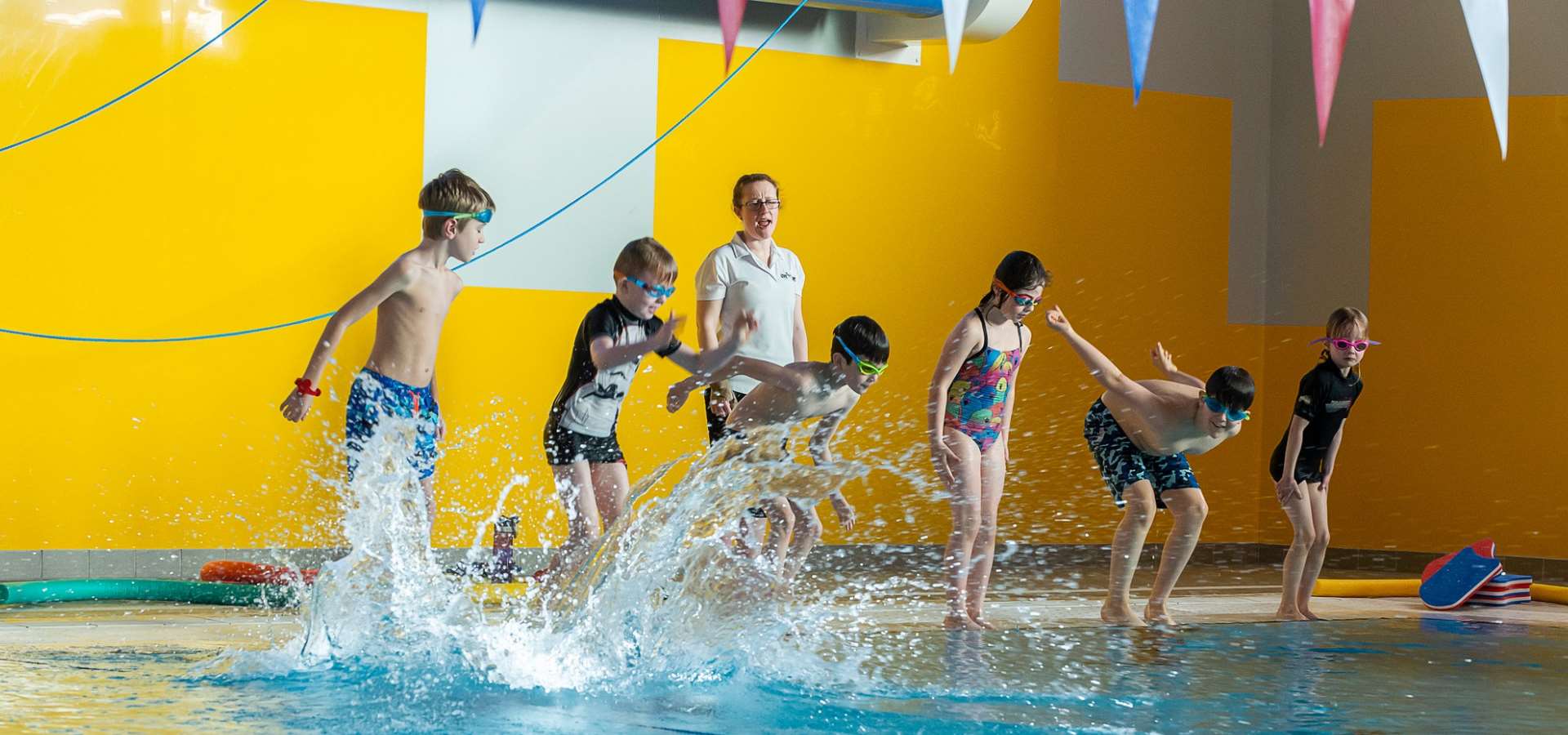 A group of children jumping into the pool