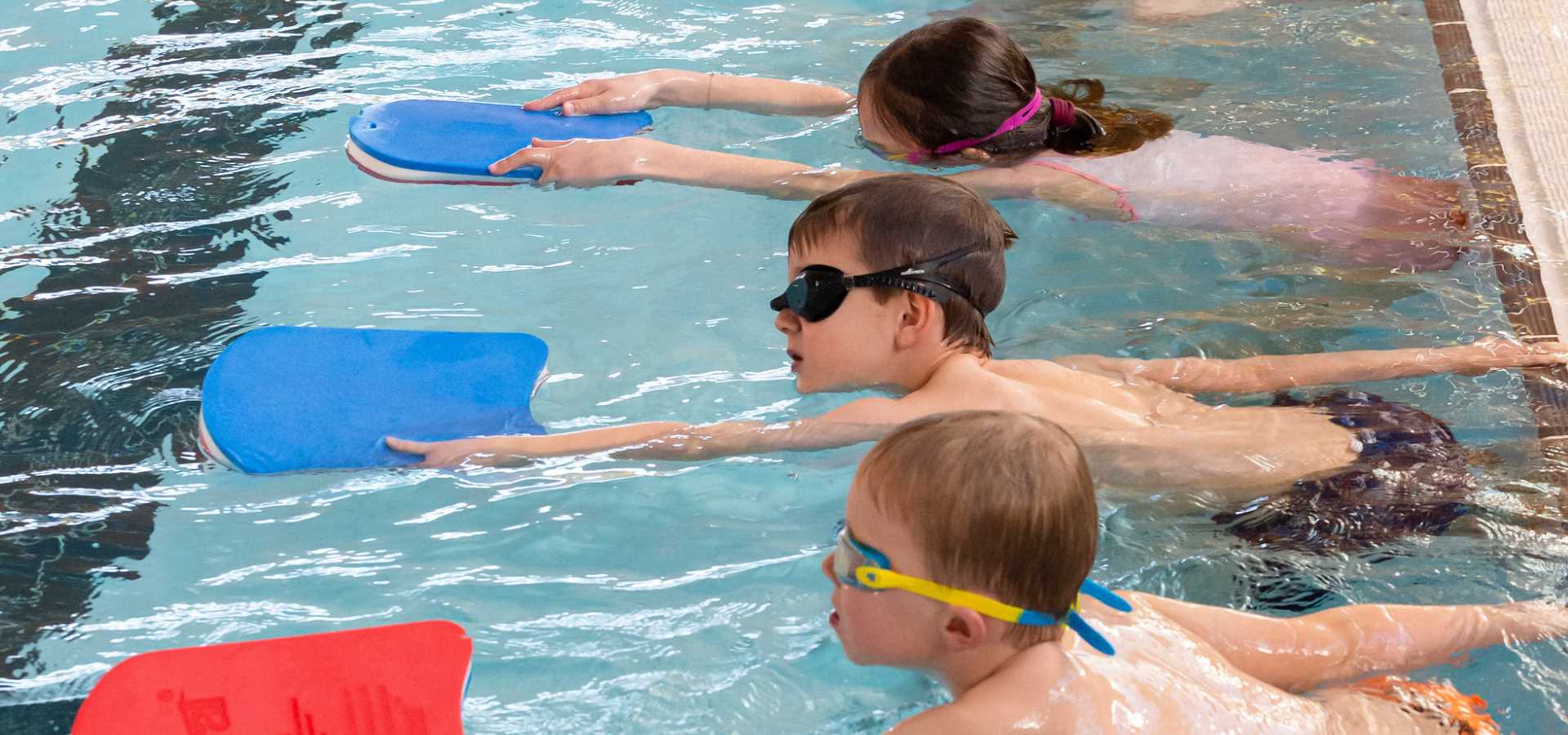 A group of children holding floats in the swimming pool