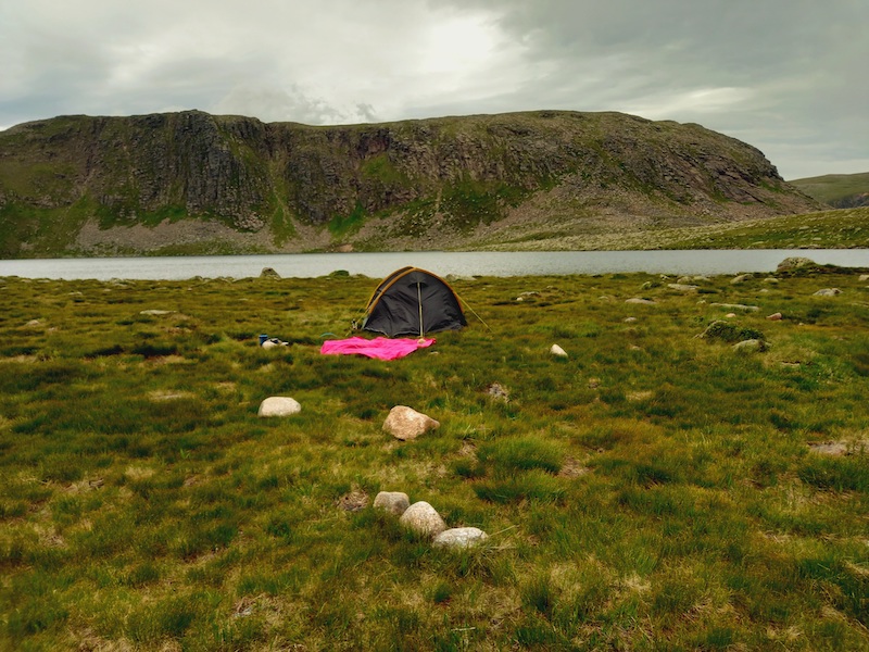 Camping tent with loch and mountain in the background