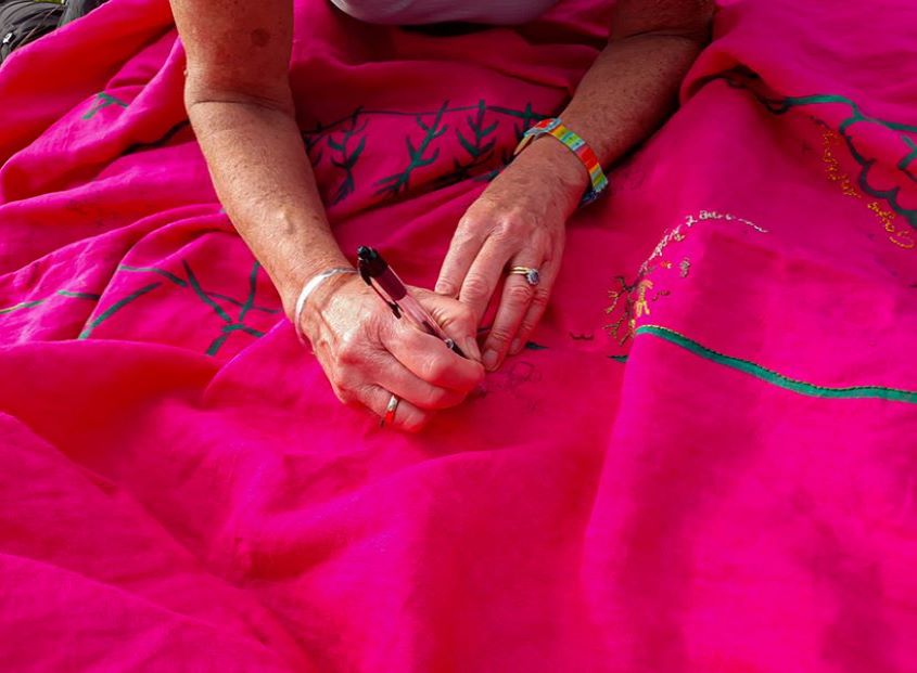hands writing on pink cloth