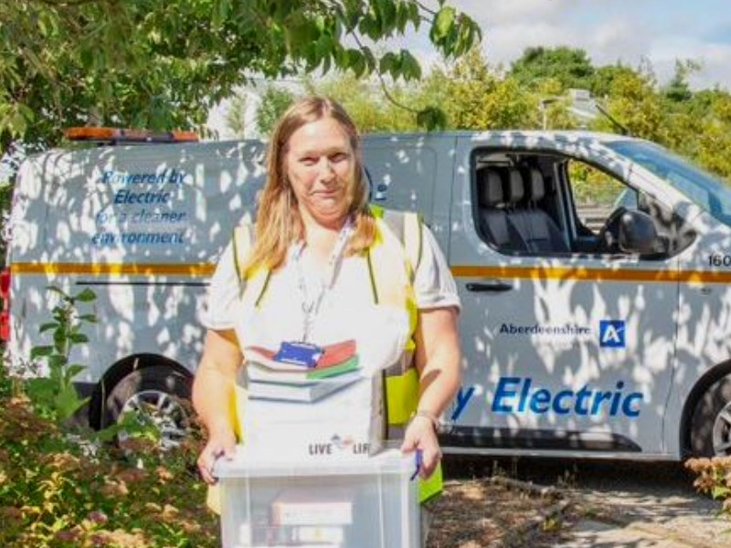 A member of the Live Life Aberdeenshire team carrying a box of books